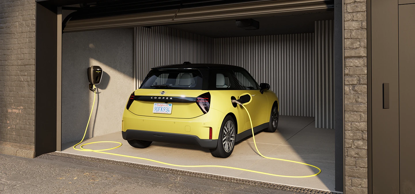 Heckansicht eines vollelektrischen MINI Cooper in Sunnyside Yellow beim Laden in einer Garage. 