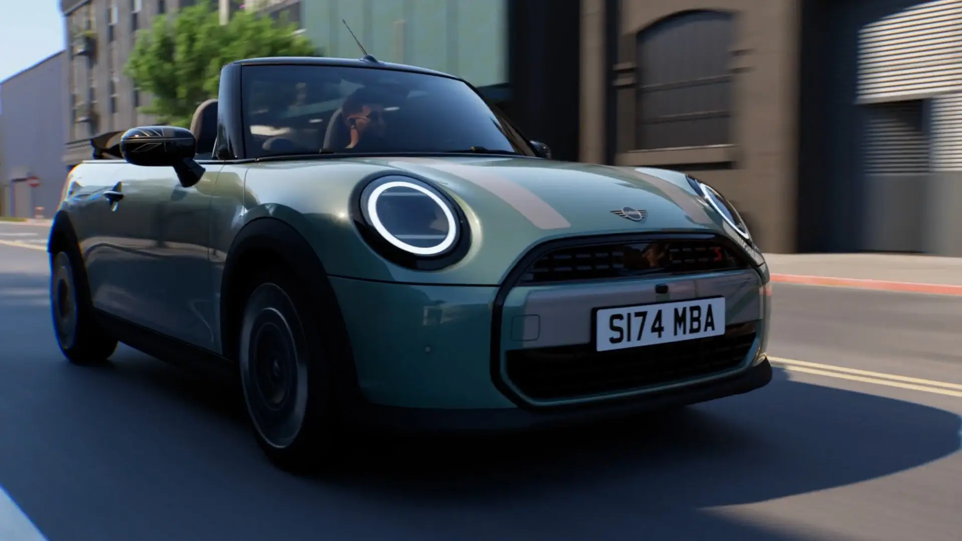 Ein MINI Cabrio in Ocean Wave Green mit weißer MINI Folierung Heritage und Union Jack Spiegelkappen fährt durch eine Stadt.