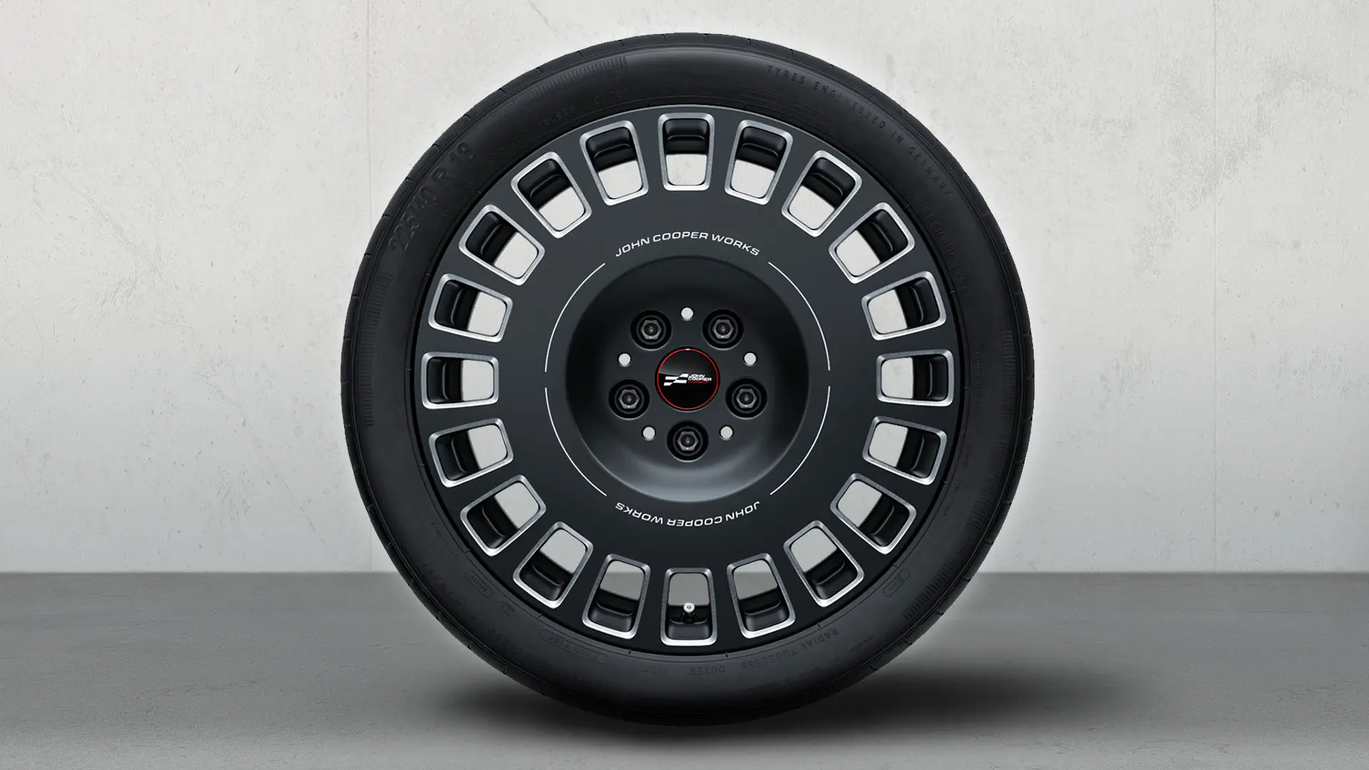 18-Zoll-Leichtmetallrad JCW Rallye Spoke 992 mit JCW-Logo und zweifarbigem Design in Frozen Midnight Grey mit glanzgefräster Oberfläche.