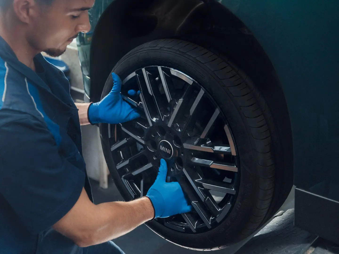 Ein MINI Servicetechniker montiert ein MINI 18-Zoll-Leichtmetallrad Night Flash Spoke Bicolour auf einen MINI Cooper Electric.