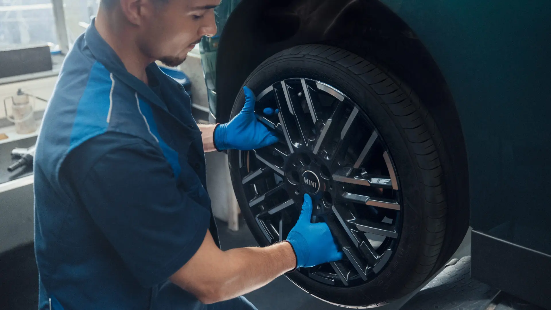 Ein MINI Servicetechniker montiert ein MINI 18-Zoll-Leichtmetallrad Night Flash Spoke Bicolour auf einen MINI Cooper Electric.