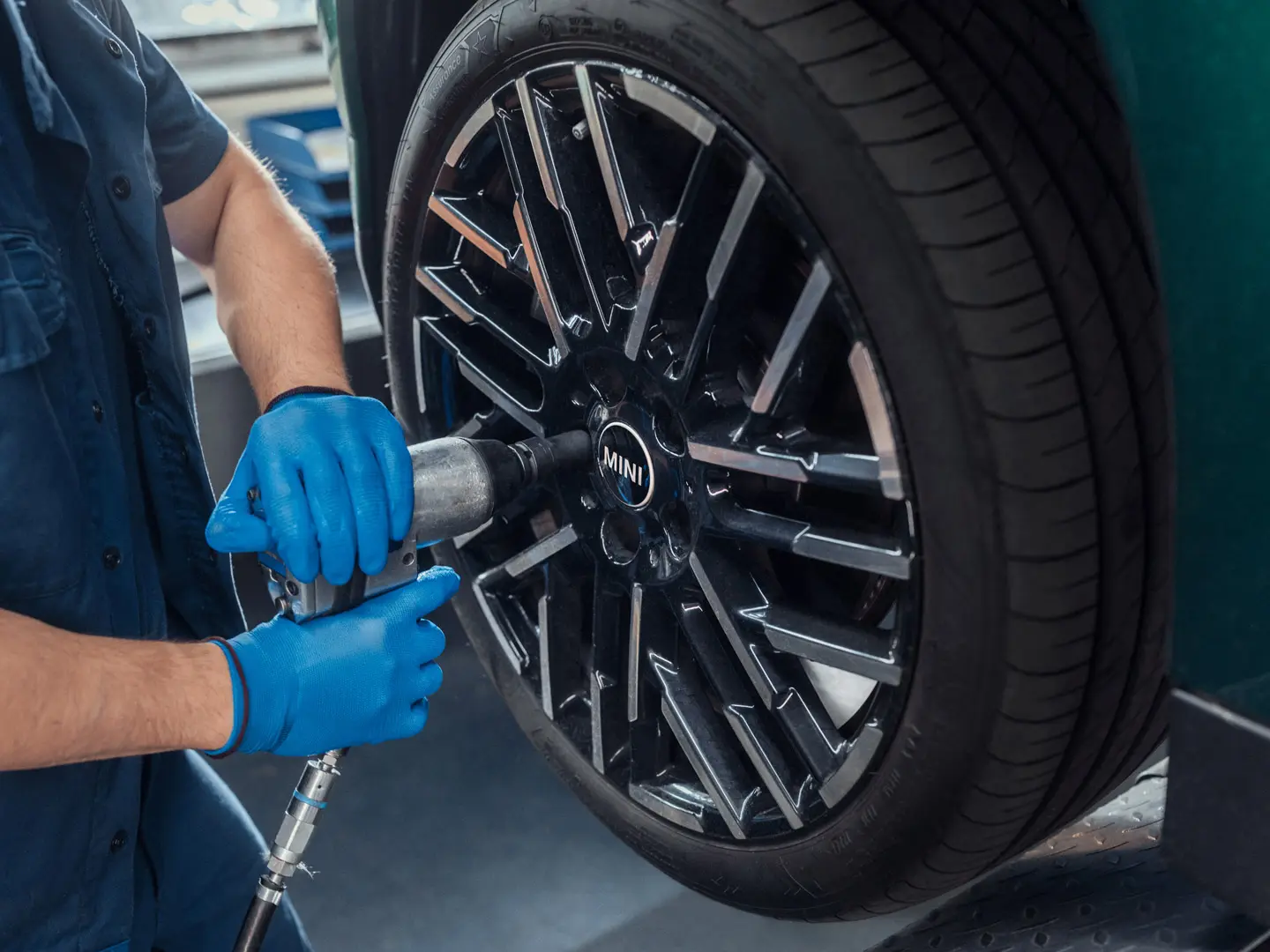 Ein Servicetechniker bei einem MINI Partner montiert ein MINI 18-Zoll-Leichtmetallrad Night Flash Spoke Bicolour auf einen MINI.