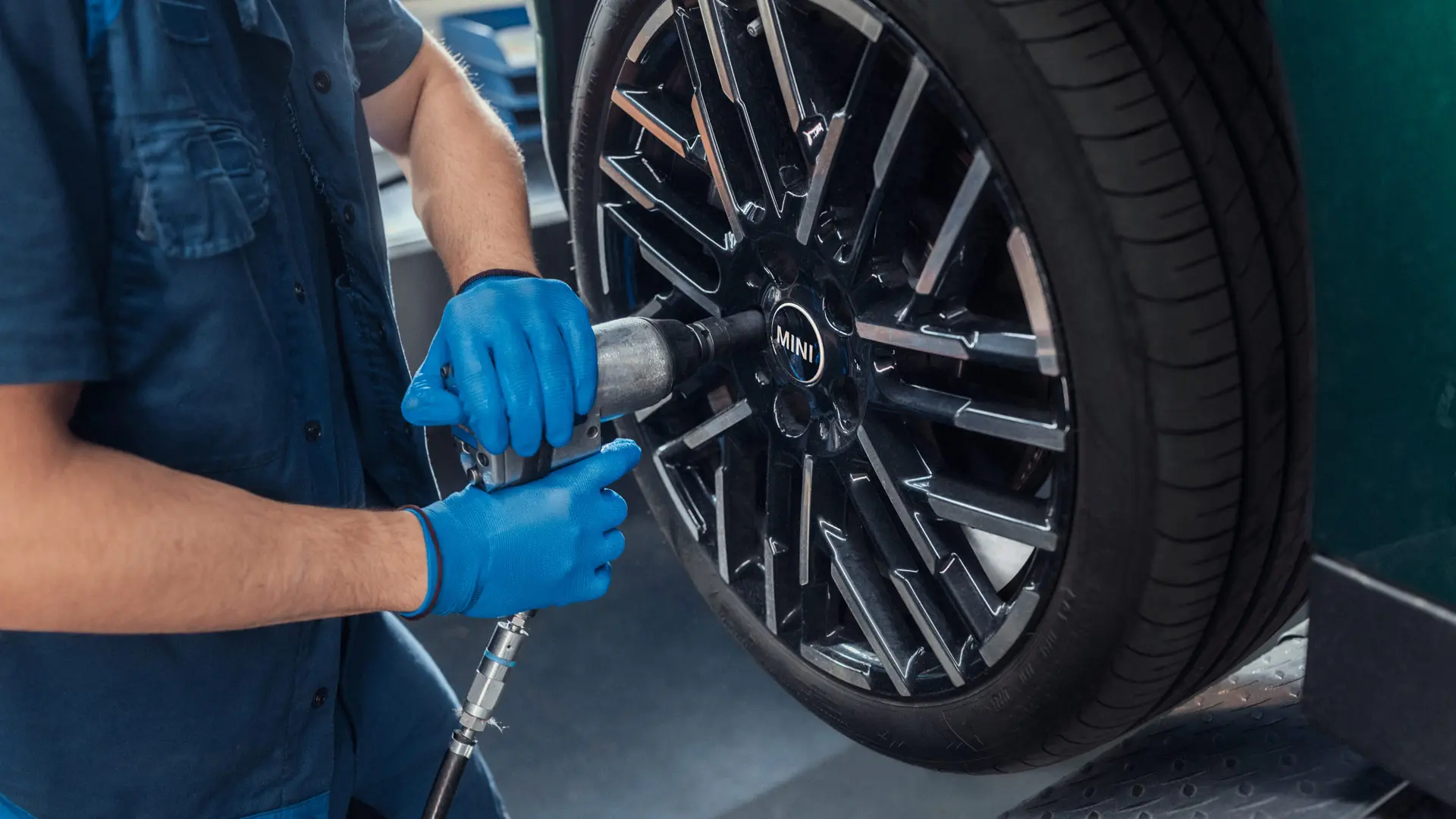Ein Servicetechniker bei einem MINI Partner montiert ein MINI 18-Zoll-Leichtmetallrad Night Flash Spoke Bicolour auf einen MINI.