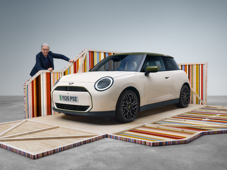 Frontansicht des vollelektrischen MINI Cooper Paul Smith Edition in Inspired White mit dem Designer Paul Smith.
